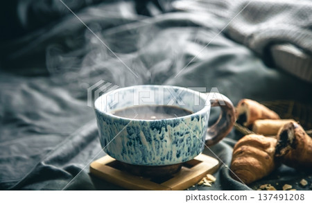A cup of hot tea and croissants on a blurred background in bed. 137491208