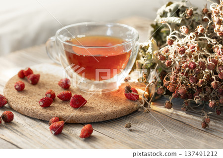 A cup of natural tea and wild strawberries, rustic still life. A cup of natural tea and wild strawberries, rustic still life. 137491212