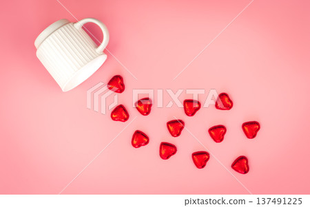 A cup and scattered heart-shaped sweets on a pink background, flat lay. 137491225