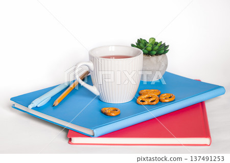 A cup of tea and notebooks on a white background, isolated, copy space. 137491253