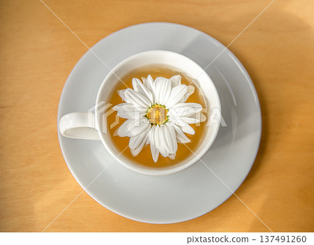 Cup of tea with chamomile flower on a wooden background, close up. Cup of tea with chamomile flower on a wooden background, close up. 137491260