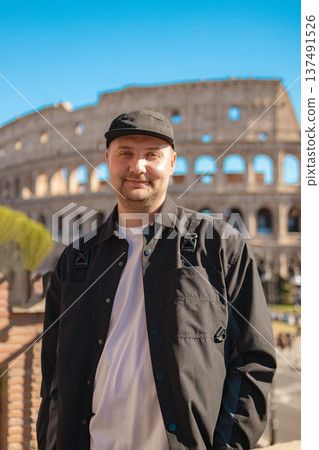 Handsome 30s tourist visiting Colosseum in Rome, Italy. Young man taking photo in front of famous Italian landmark Handsome 30s tourist visiting Colosseum in Rome, Italy. Young man taking photo in front of famous Italian landmark 137491526