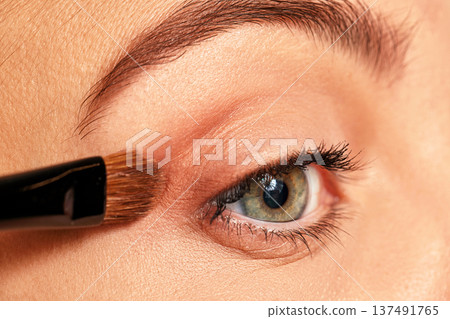 Woman applying cosmetic product with makeup brush on eyelid for beauty Woman applying cosmetic product with makeup brush on eyelid for beauty 137491765