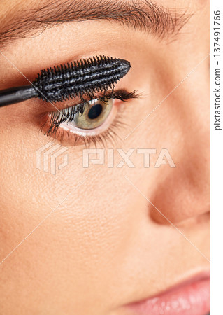 Woman applying black mascara on her eyelashes, focusing on beauty and cosmetics Woman applying black mascara on her eyelashes, focusing on beauty and cosmetics 137491766