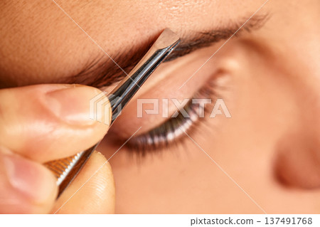 Close-up of person's hand using tweezers to remove stray eyebrow hairs near eye Close-up of person's hand using tweezers to remove stray eyebrow hairs near eye 137491768