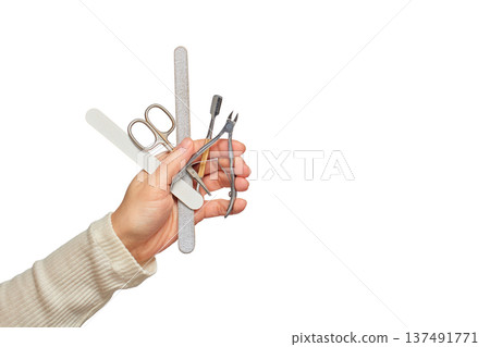 Hand holding a variety of nail care instruments for beauty and grooming 137491771