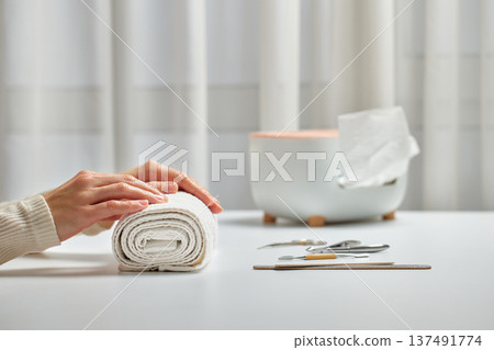 Woman enjoying a self-care beauty routine with a hand on a rolled white towel 137491774