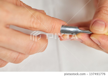 Woman performing a self-care manicure, pushing back cuticles on her nails Woman performing a self-care manicure, pushing back cuticles on her nails 137491776