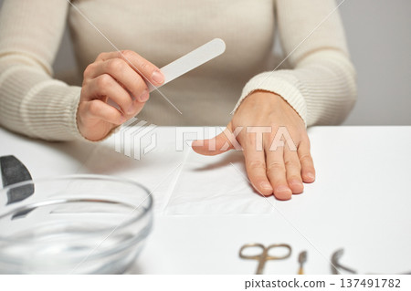 Woman filing fingernails during personal self-care beauty routine Woman filing fingernails during personal self-care beauty routine 137491782