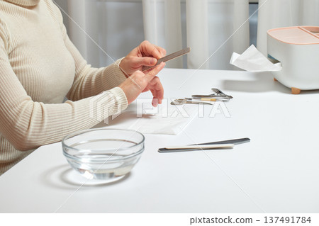 Woman filing her fingernails with an emery board for personal nail care Woman filing her fingernails with an emery board for personal nail care 137491784