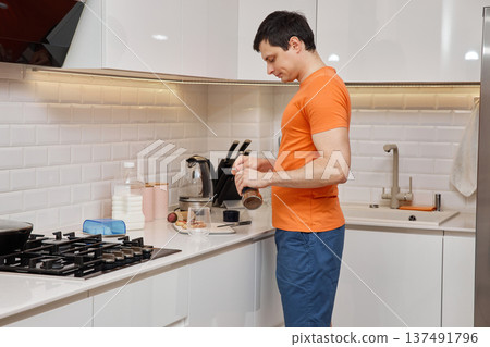 Man slicing sausage for breakfast toast in bright domestic kitchen Man slicing sausage for breakfast toast in bright domestic kitchen 137491796