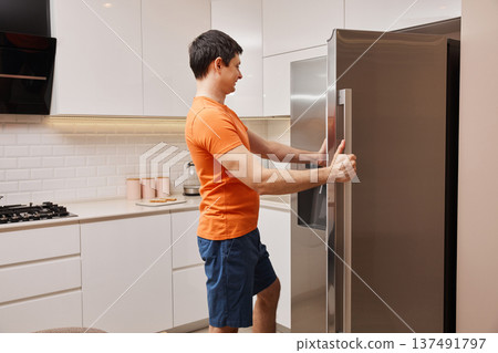 Man reaching for a snack, dealing with hunger in a home kitchen Man reaching for a snack, dealing with hunger in a home kitchen 137491797