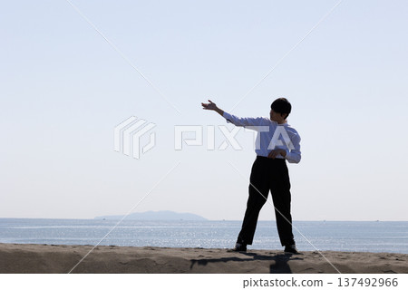Silhouette of a man raising his right hand slightly higher than horizontal Silhouette of a man raising his right hand slightly higher than horizontal 137492966