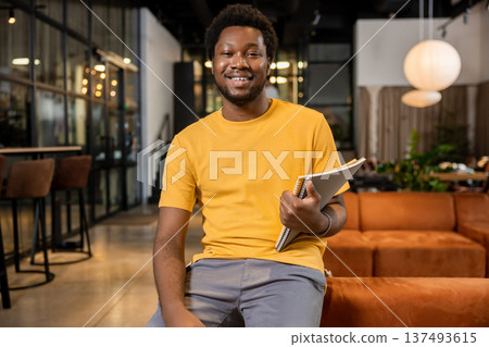 Young professional sitting comfortably on couch with notepad in hands in coworking office Young professional sitting comfortably on couch with notepad in hands in coworking office 137493615