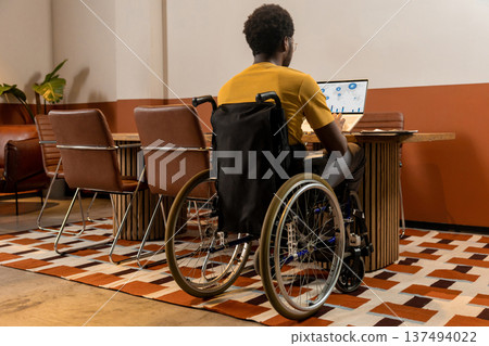 Focused man in wheelchair using laptop working with business data Focused man in wheelchair using laptop working with business data 137494022