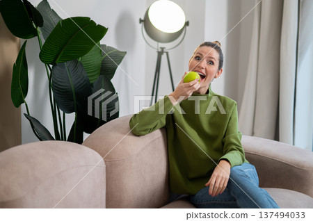 Young smiling woman in green with apple in hand 137494033