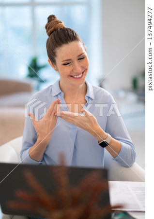 Smiling cute young woman explaining something on video call by sign language 137494277