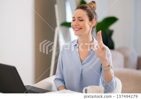 Smiling cute young woman explaining something on video call by sign language Smiling cute young woman explaining something on video call by sign language 137494279