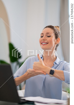 Smiling cute young woman explaining something on video call by sign language 137494282