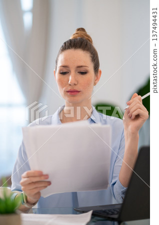 Young business woman looking busy while working from her home office Young business woman looking busy while working from her home office 137494431