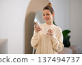 Cute caucasian woman in white sweater with a cup in hands 137494737