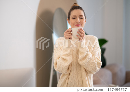 Cute caucasian woman in white sweater with a cup in hands 137494757