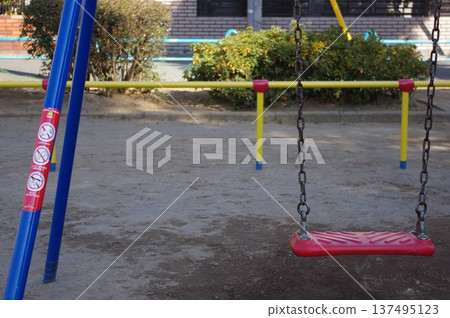 午後空蕩蕩的公園裡,一個紅色的鞦韆靜靜佇立。 午後空蕩蕩的公園裡,一個紅色的鞦韆靜靜佇立。 137495123