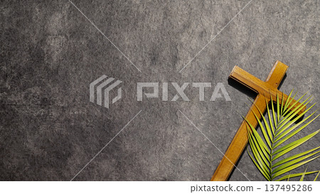 A wooden cross and a green palm leaf on a textured dark stone surface with copy space. Symbolizing Palm Sunday and the start of Holy Week in the Christian faith A wooden cross and a green palm leaf on a textured dark stone surface with copy space. Symbolizing Palm Sunday and the start of Holy Week in the Christian faith 137495286