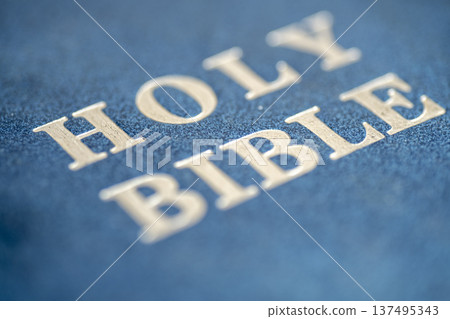 Detailed macro shot of the embossed 'HOLY BIBLE' text in silver on a textured blue leather-bound book cover. Shallow depth of field highlights the sacred scripture title Detailed macro shot of the embossed 'HOLY BIBLE' text in silver on a textured blue leather-bound book cover. Shallow depth of field highlights the sacred scripture title 137495343