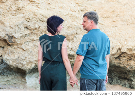 A man and a woman in casual clothes hugging near rocks on a beach A man and a woman in casual clothes hugging near rocks on a beach 137495960