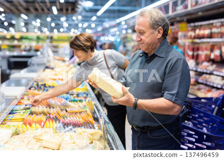 Elderly man choose cheese in supermarket Elderly man choose cheese in supermarket 137496459