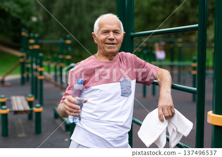 Elderly man standing on outdoor sports ground Elderly man standing on outdoor sports ground 137496537