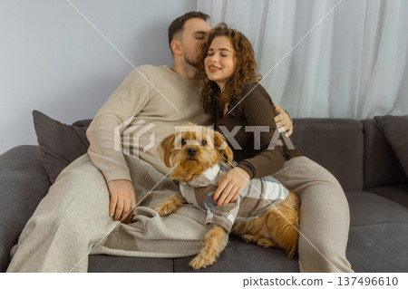 Happy couple relaxing at home with cute dog sitting on sofa in modern living room Happy couple relaxing at home with cute dog sitting on sofa in modern living room 137496610