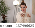 Woman with hair bun looking focused while recording a voice message 137496625