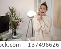 Woman in white sweater talking on the phone and looking surprised 137496626