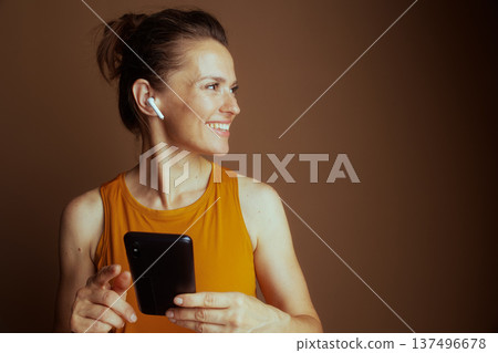 Woman with Earbud Engaging with Smartphone 137496678