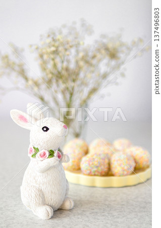 Easter bunny figurine with pastel sprinkle treats and floral background for spring decor Easter bunny figurine with pastel sprinkle treats and floral background for spring decor 137496803
