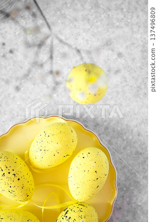 Bright yellow speckled Easter eggs on a decorative plate with spring ribbon 137496809