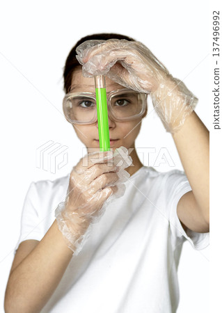 Young scientist holding a bright green test tube in a lab, wearing protective gloves and goggles 137496992