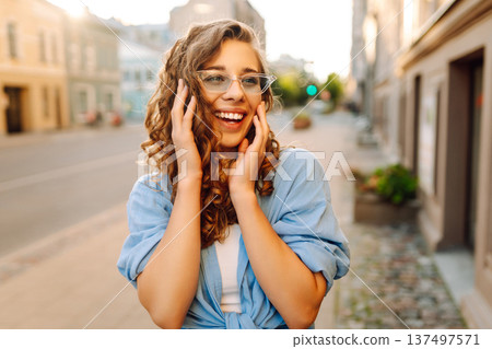 Fashionable young woman in good mood posing outdoors. Sunny day. Concept of lifestyle, fashion Fashionable young woman in good mood posing outdoors. Sunny day. Concept of lifestyle, fashion 137497571