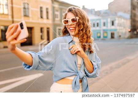 Beautiful woman traveler using phone, taking selfie, walking on the old town street. Blogging Beautiful woman traveler using phone, taking selfie, walking on the old town street. Blogging 137497597