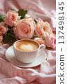 Cup of latte with heart latte art surrounded by pink roses and soft fabric 137498145