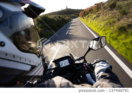 Driver riding motorcycle on empty asphalt road, handlebars view , spring mountains Driver riding motorcycle on empty asphalt road, handlebars view , spring mountains 137498791