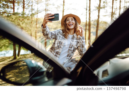Selfie in nature. Woman tourist standing near car and enjoy nature. Active lifestyle, travel. 137498798