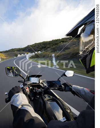 Driver riding motorcycle on empty asphalt road, handlebars view , spring mountains Driver riding motorcycle on empty asphalt road, handlebars view , spring mountains 137498806