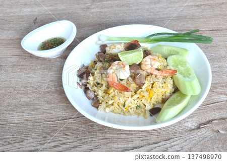 fried rice shrimp topping piece of beef meat and egg with slice cucumber couple lemon on plate dressing chili fish sauce cup 137498970