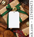 Blank paper gift tag on wrapped Christmas present near rustic wooden decor, holiday mockup 137499473