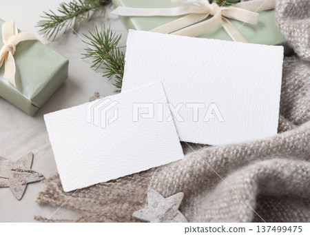 Christmas cards mockup on wrapped sage green gift box with ribbon bow and fir branch, top view Christmas cards mockup on wrapped sage green gift box with ribbon bow and fir branch, top view 137499475