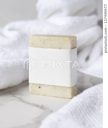 Mockup of beige solid soap bar with blank paper label near white bath towel, personal care packaging Mockup of beige solid soap bar with blank paper label near white bath towel, personal care packaging 137499477
