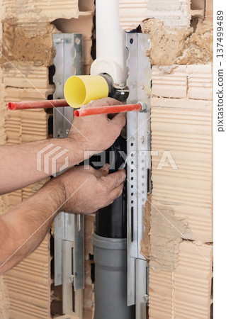 Plumber installing concealed toilet cistern and drain pipes inside brick wall, close up of hands Plumber installing concealed toilet cistern and drain pipes inside brick wall, close up of hands 137499489